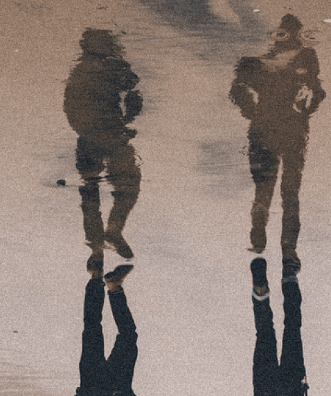 An image of a person walking with a reflection in the water of that person as a soldier